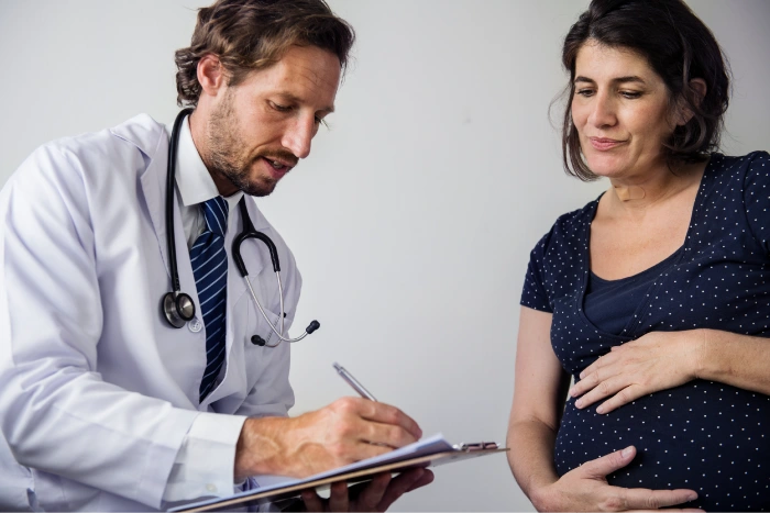 Healthcare professional reviewing information on a clipboard while discussing pregnancy and fertility planning with a patient